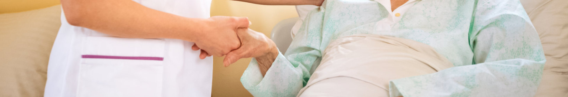 caregiver and senior woman holding hands