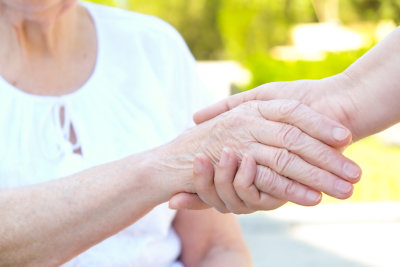 Old and young holding hands on light background close up
